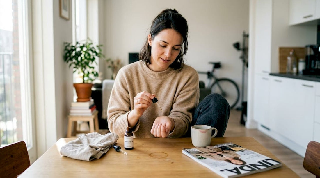 Een vrouw brengt parfumolie aan terwijl ze aan de eettafel zit.